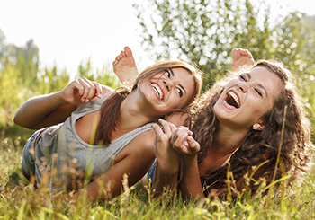 two girlfriends lying down on grass